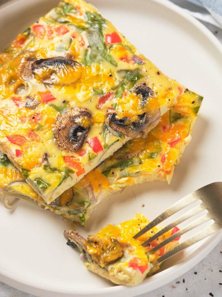 A slice of sheet pan eggs on a plate with a fork.