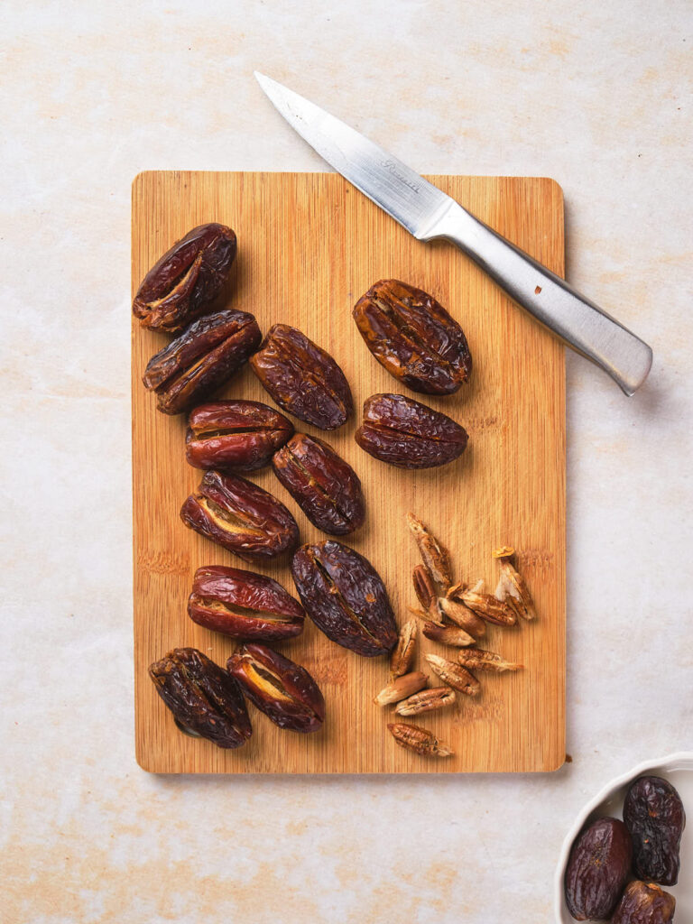 Dates on a wooden board next to a knife.