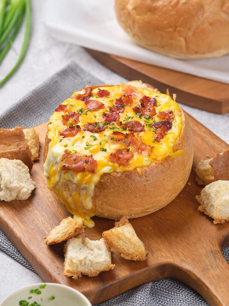 Bread bowl filled with melted cheese, bacon, and herbs.