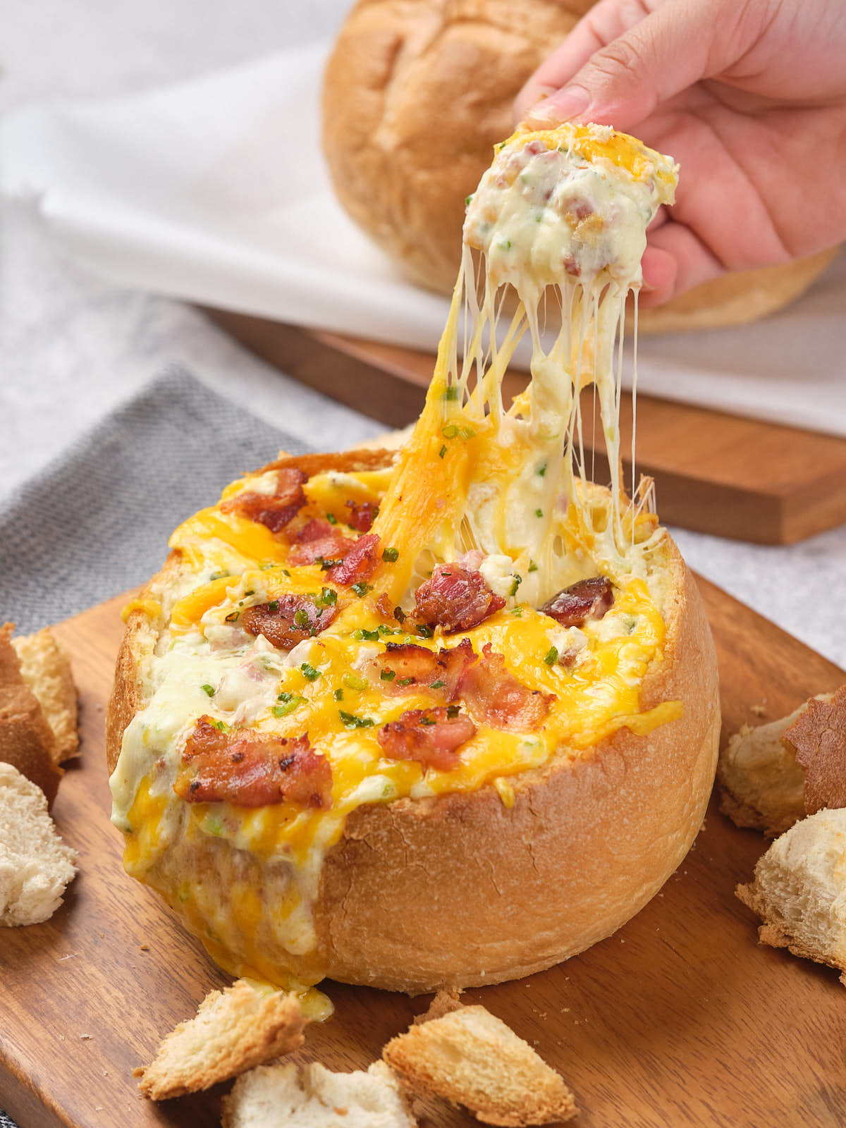 A bread bowl filled with melted cheese, bacon, and herbs.