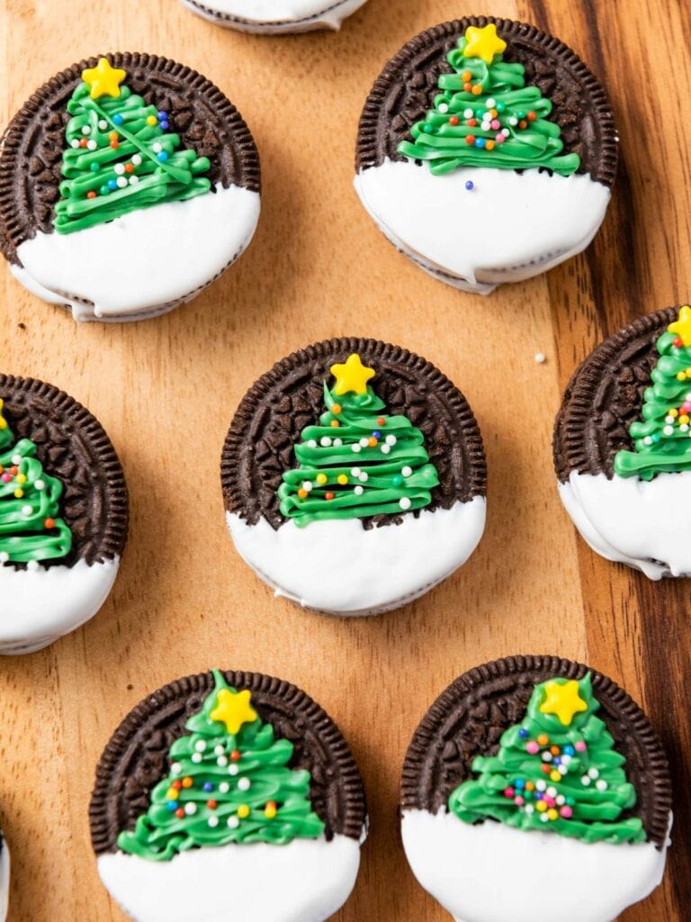 Cookies with white icing and green Christmas tree decorations topped with yellow stars, arranged on a wooden surface.