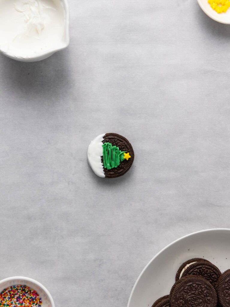 A cookie decorated with white icing, a green Christmas tree, and a yellow star.