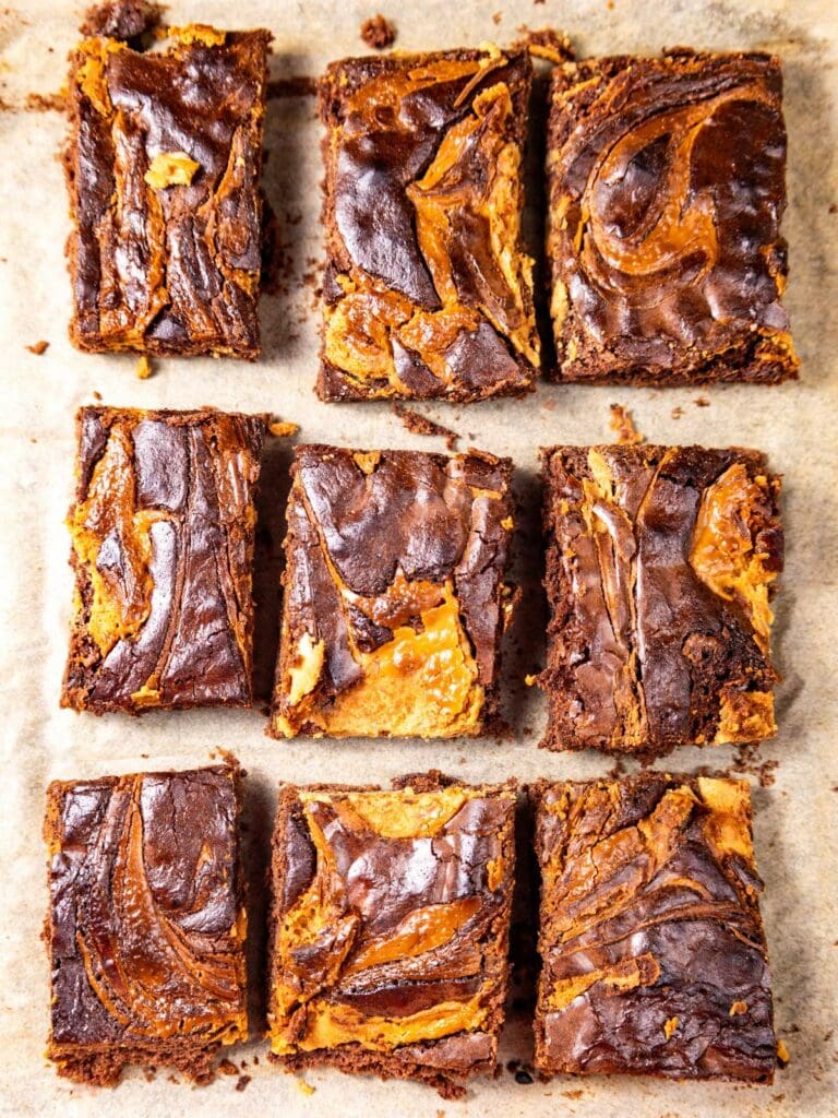 Nine peanut butter brownies arranged on parchment paper.