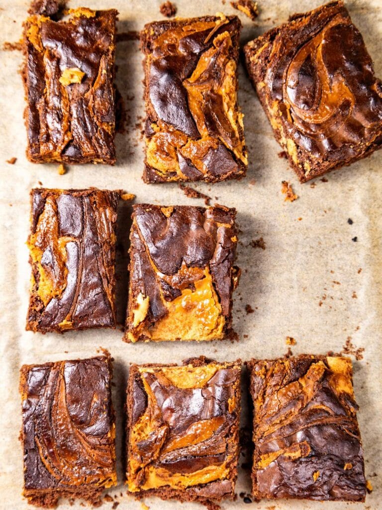 Eight peanut butter brownies on parchment paper.