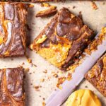 Close-up of cut brownies with a swirl pattern on parchment paper.