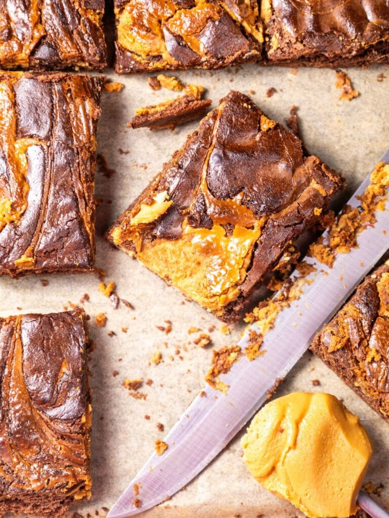 Close-up of cut brownies with a swirl pattern on parchment paper.