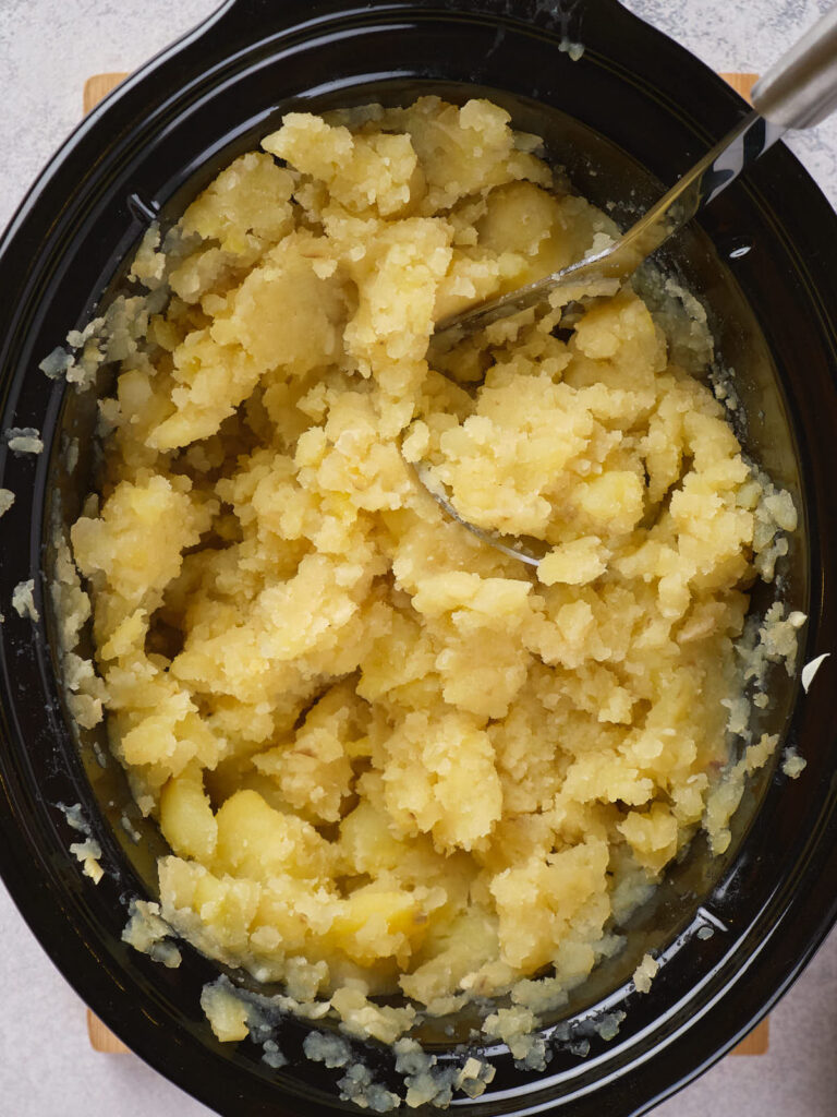 A pot of mashed potatoes with a serving spoon.