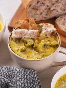 A bowl of broccoli cheddar soup with bread pieces on top