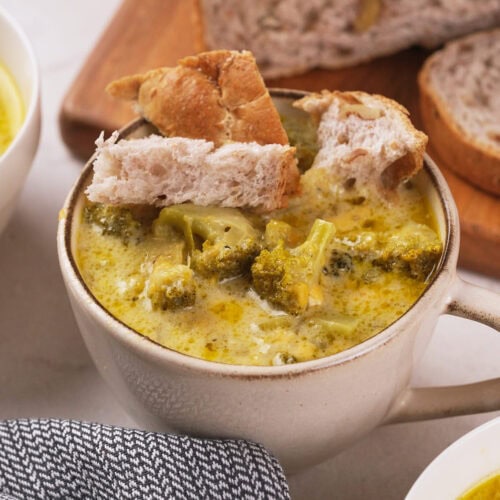 A bowl of broccoli cheddar soup with bread pieces on top