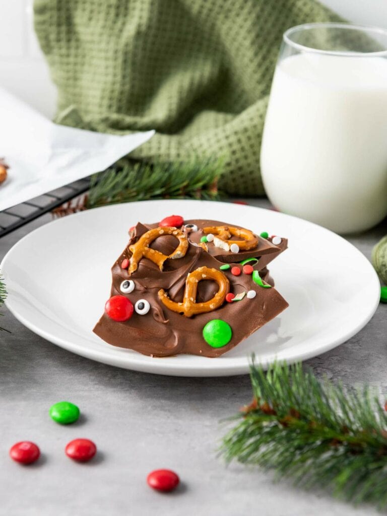 A plate of reindeer chocolate bark topped with pretzels and colorful candies.