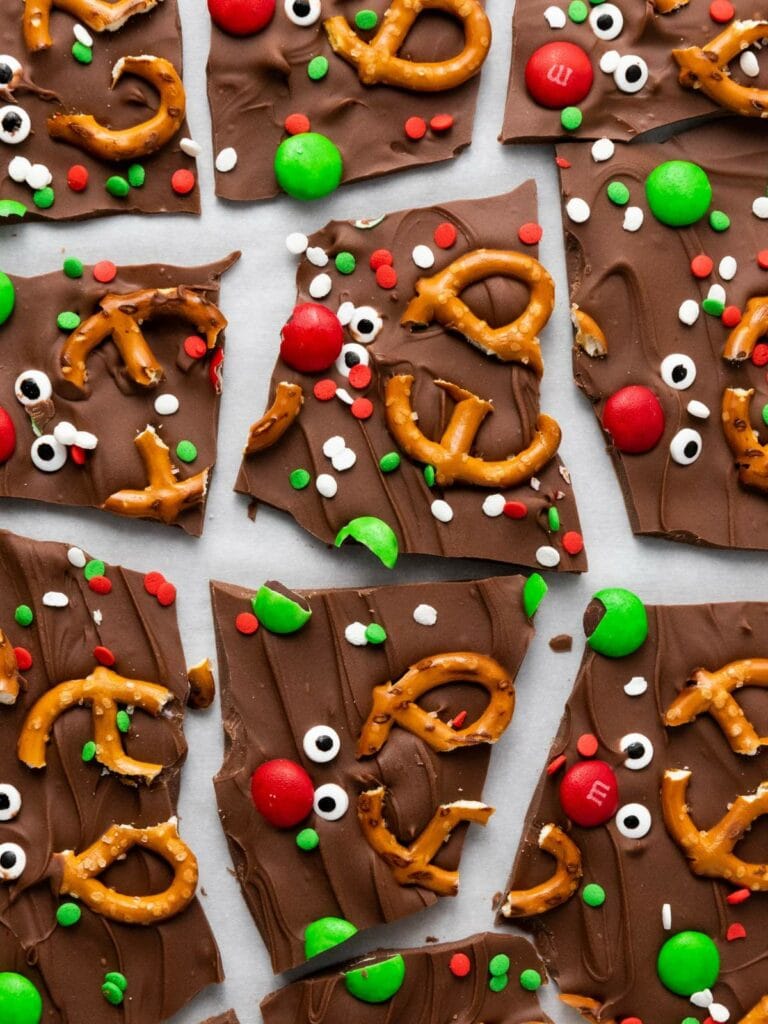 Chocolate bark pieces topped with pretzels, red and green candies, and sprinkles.