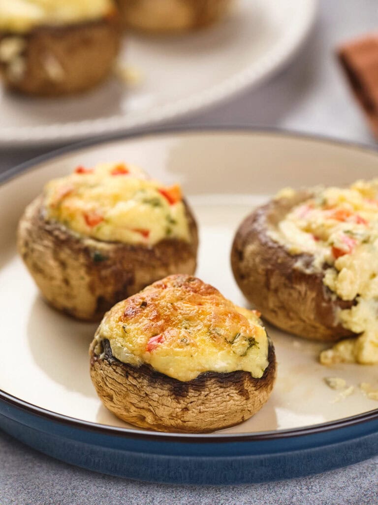 Stuffed mushrooms on a plate, filled with a mixture of cheese and vegetables.