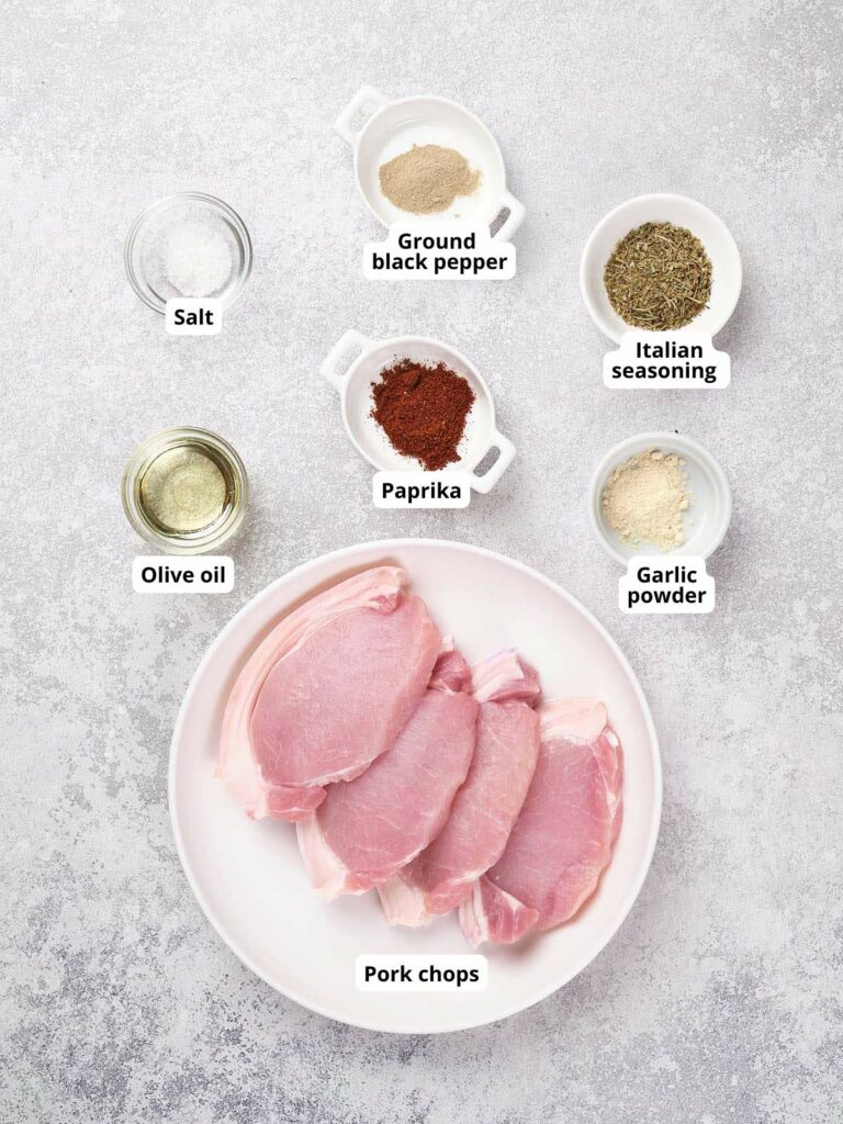 Ingredients for a pork chop recipe on a gray background.