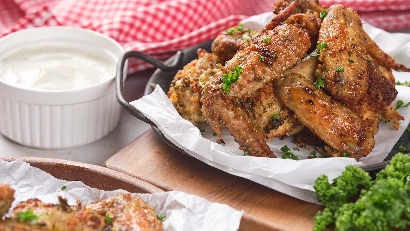 A plate of  baked chicken wings garnished with parsley on parchment paper.