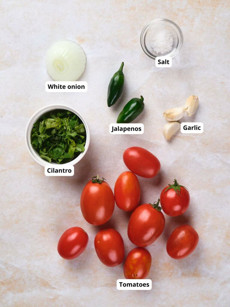 Ingredients for homemade salsa on a surface, all labeled.