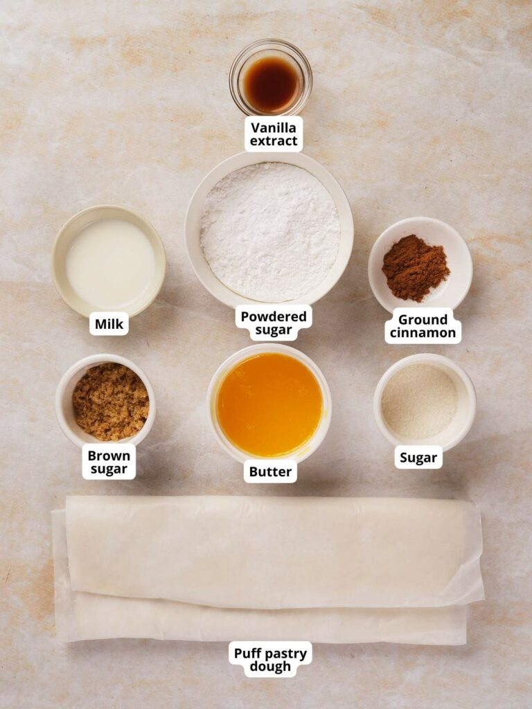 Ingredients for puff pastry cinnamon rolls are arranged on a surface.