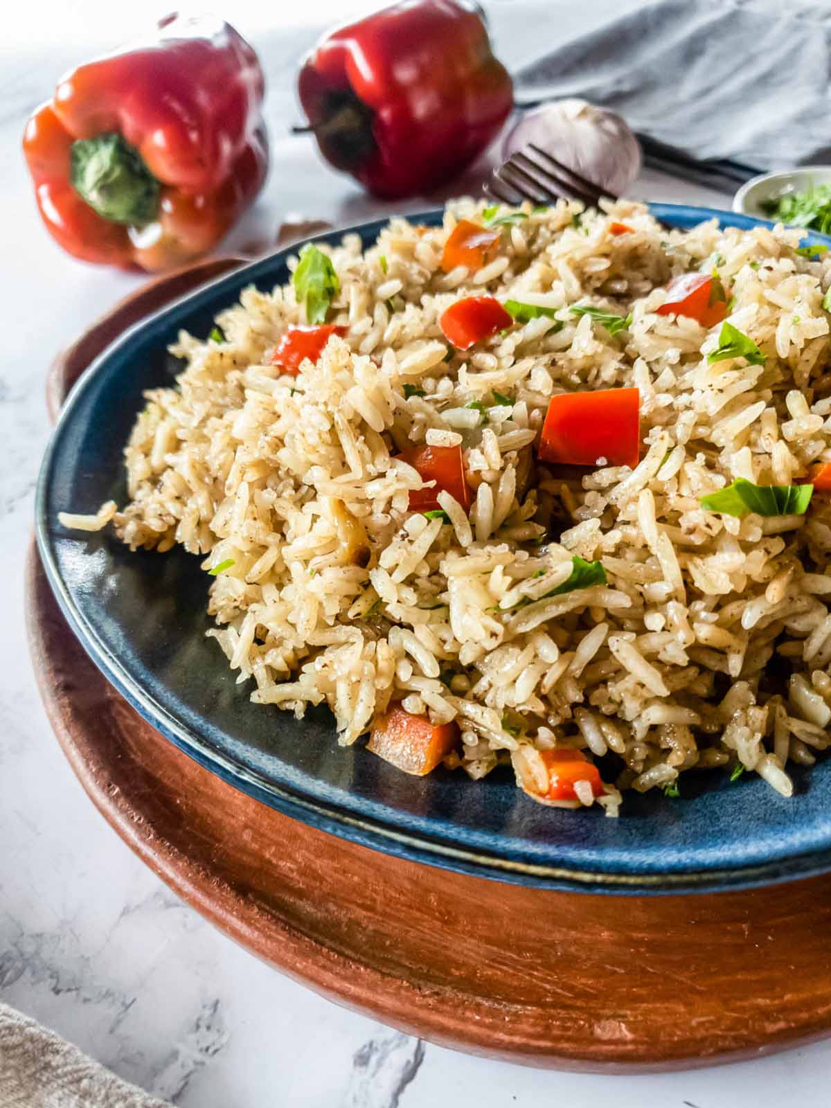 A plate of rice pilaf mixed with red bell pepper pieces and garnished with herbs.