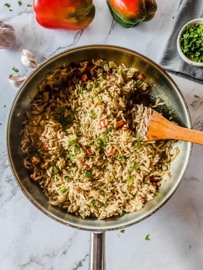 A skillet of cooked rice mixed with chopped vegetables, garnished with parsley.