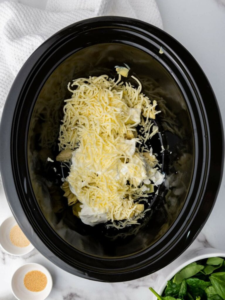 Slow cooker with shredded cheese and other ingredients.