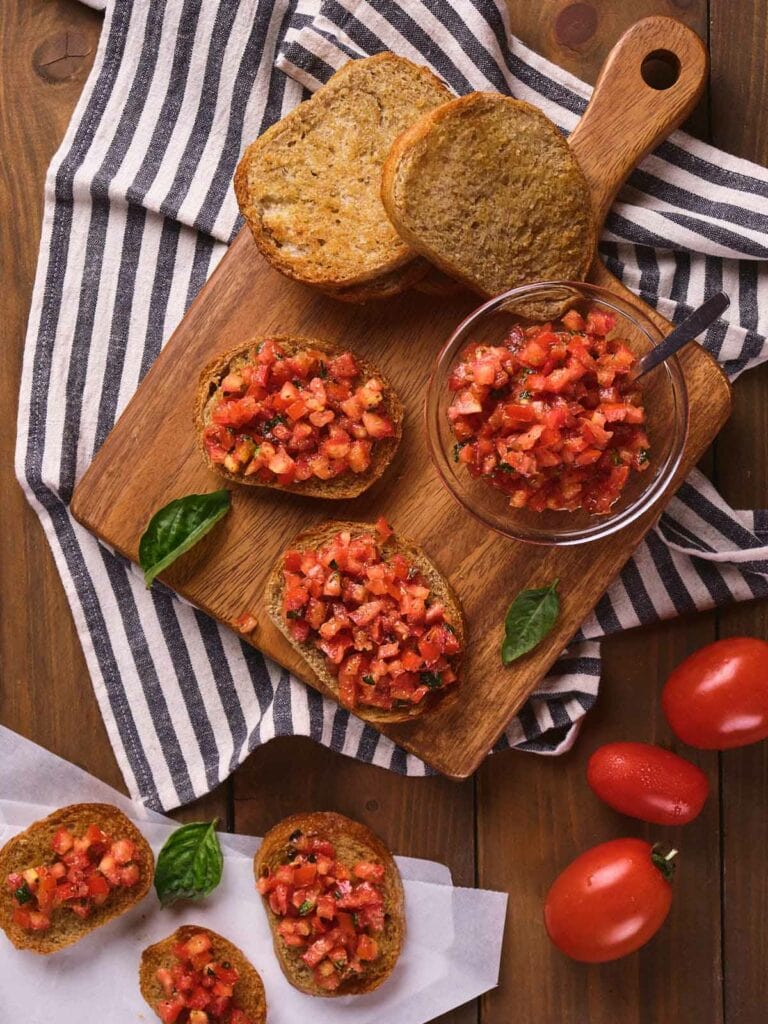 Toasted bread with tomato bruschetta on a wooden board.