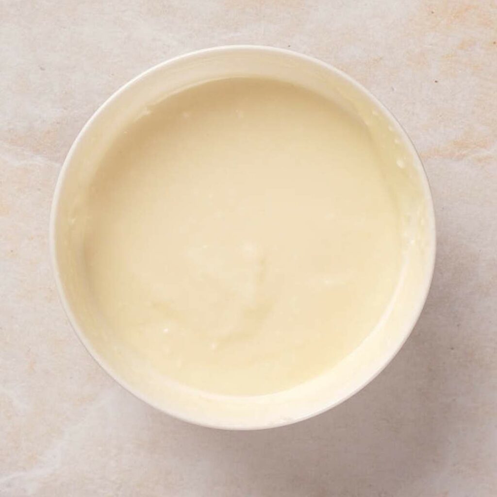 A bowl of smooth, creamy batter on a light surface.