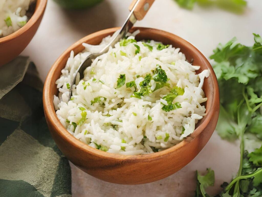 A wooden bowl filled with cilantro lime rice garnished with chopped green herbs.