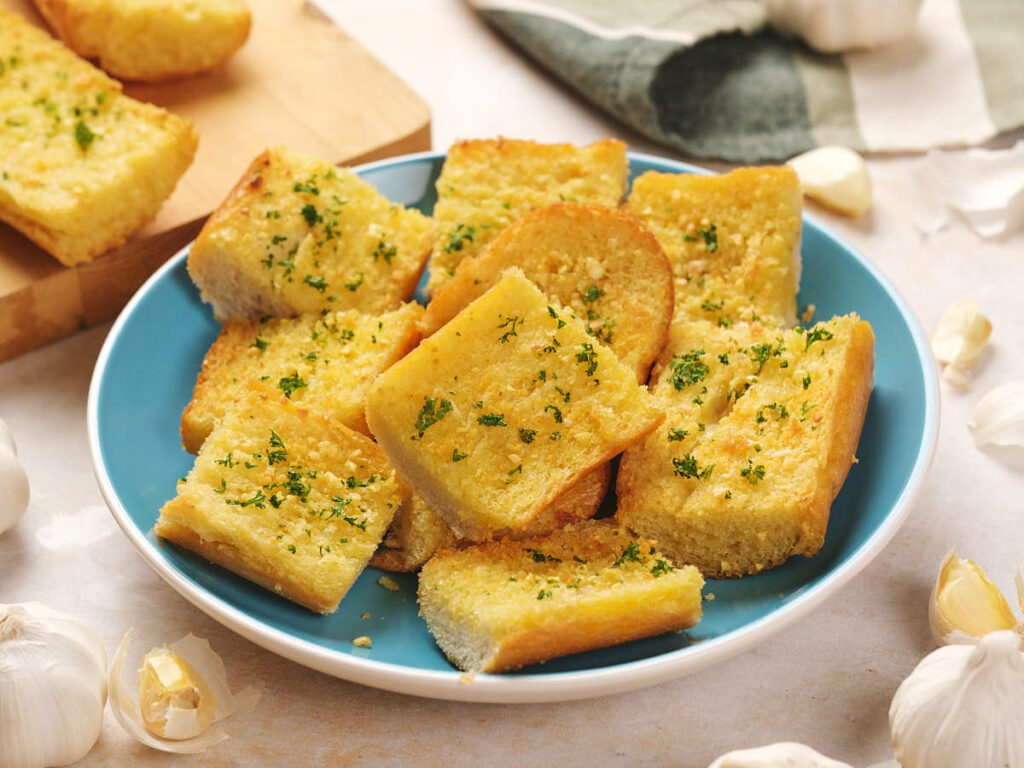 A blue plate with slices of garlic bread garnished with parsley.