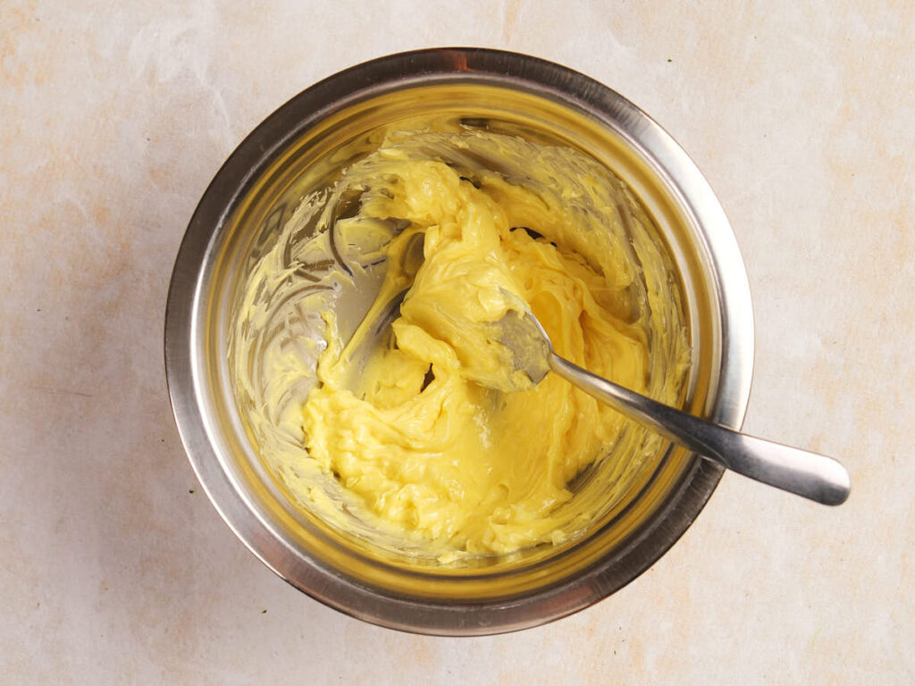 Metal bowl containing whipped butter with a spoon inside.