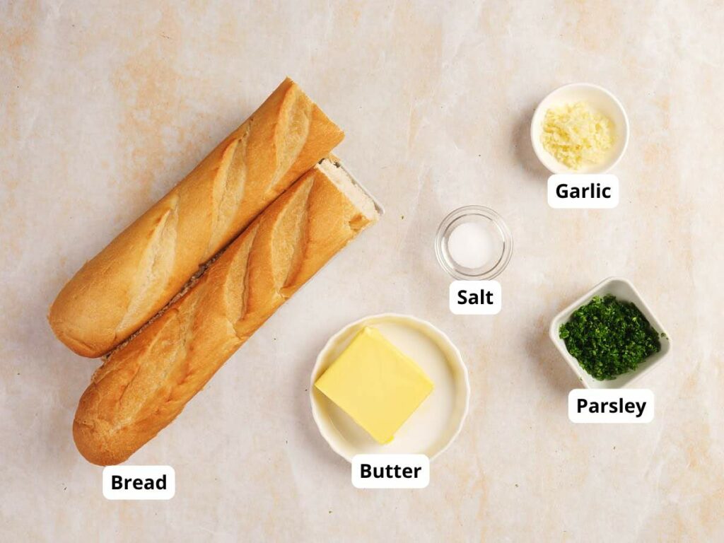 Labeled ingredients for garlic bread on a light surface.