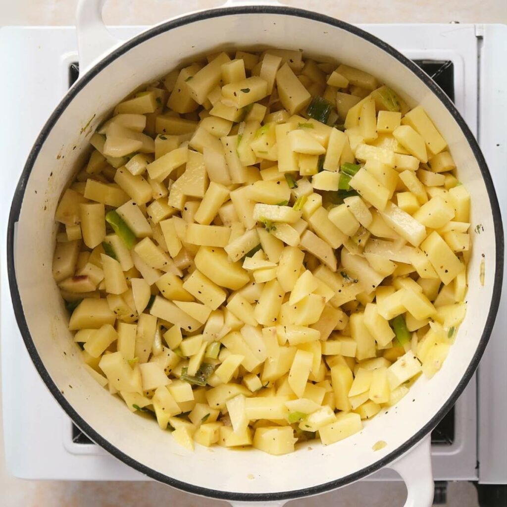 A pot filled with diced potatoes and herbs, sitting on a white stove.