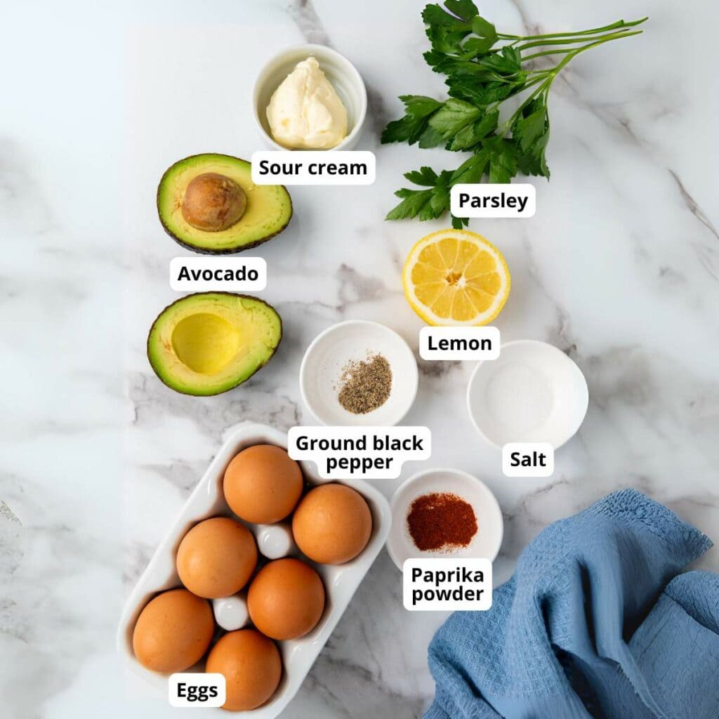 Ingredients for avocado deviled eggs on a marble countertop.