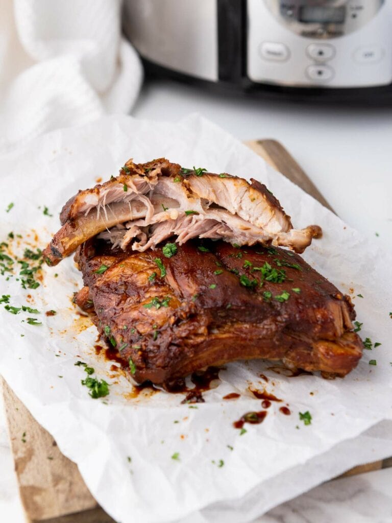 Baby back ribs garnished with chopped herbs are placed on parchment paper.