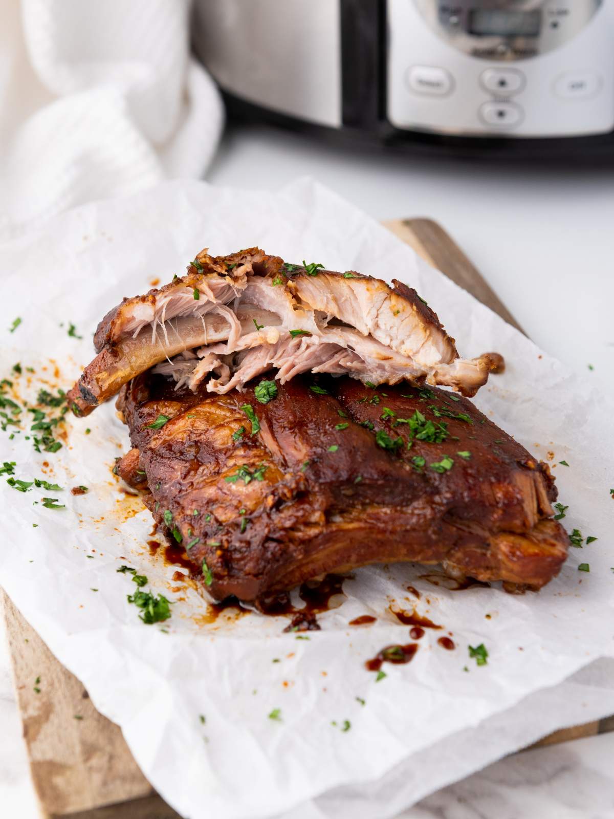 Baby back ribs garnished with chopped herbs are placed on parchment paper.