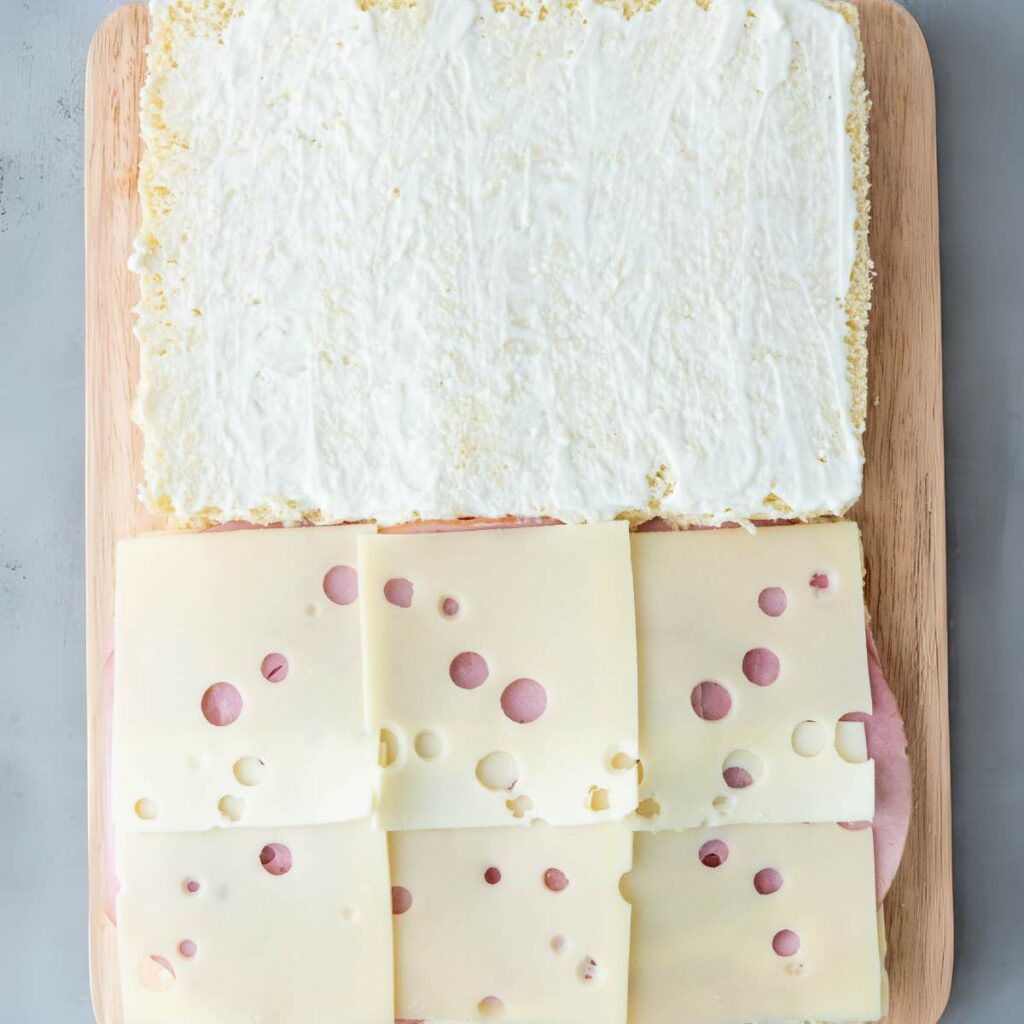 A partially assembled sandwich on a wooden board.