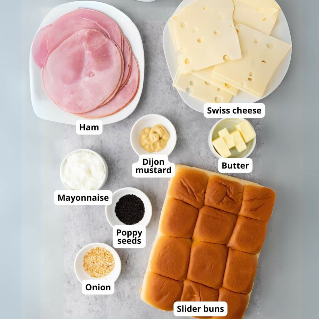 Ingredients for sliders: sliced ham, Swiss cheese, slider buns, mayonnaise, Dijon mustard, butter, poppy seeds, and onions.