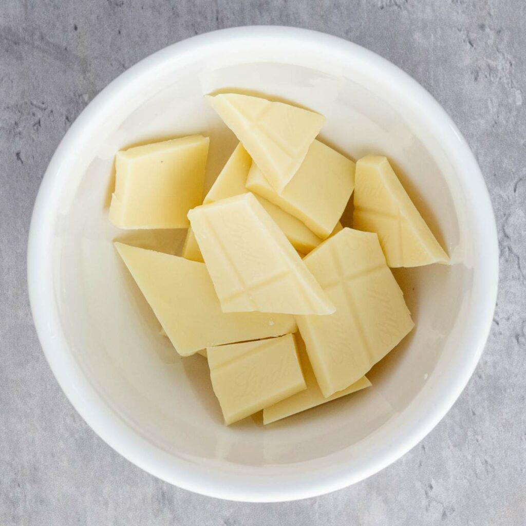 A white bowl containing several pieces of white chocolate on a gray surface.