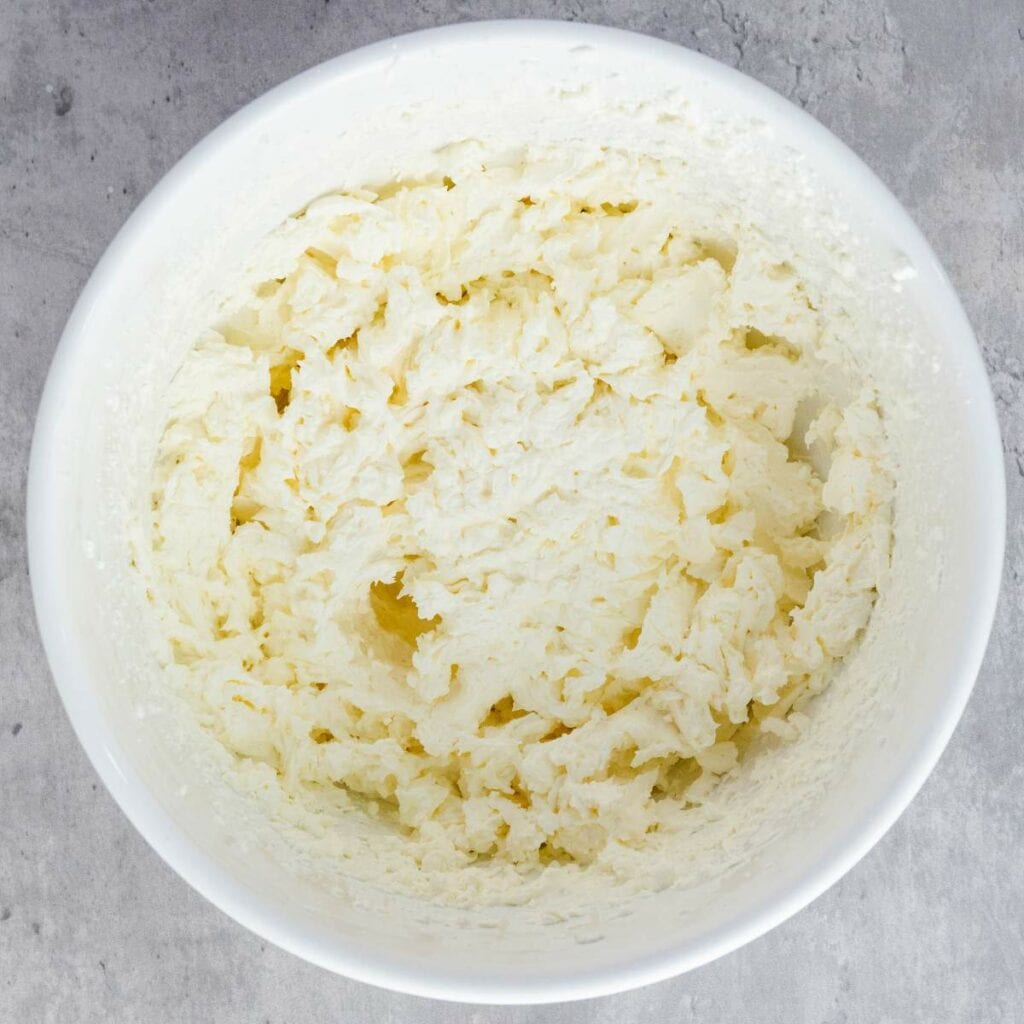 A white bowl filled with creamed butter and sugar on a gray countertop.