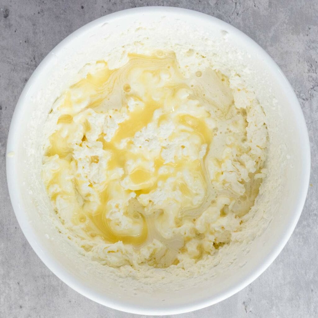 A white bowl containing a mixture of butter and separated buttermilk on a gray countertop.