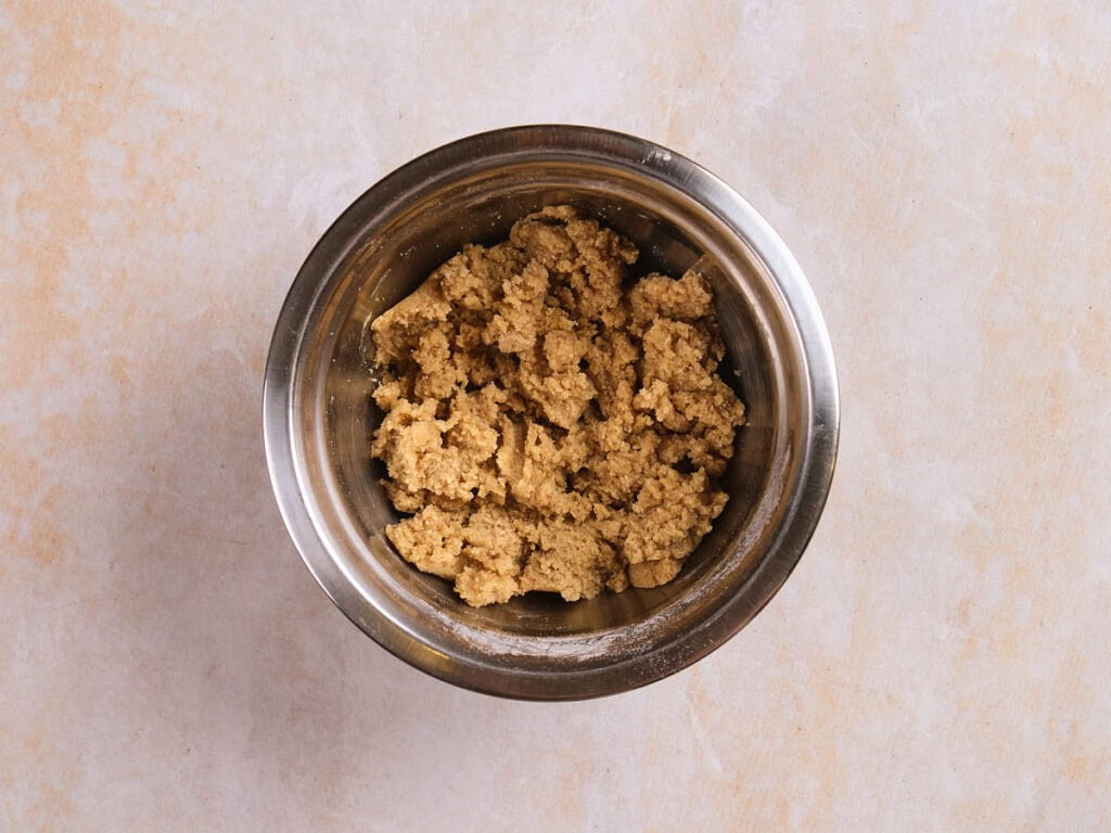 A metal mixing bowl containing raw cookie dough.