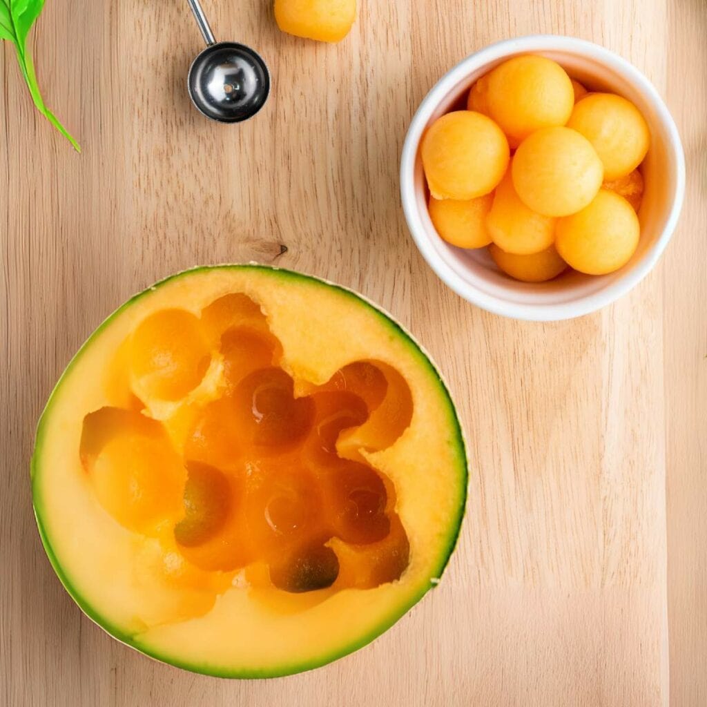 A halved cantaloupe melon with round melon balls scooped out.