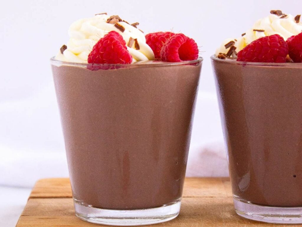 Cottage cheese pudding topped with whipped cream, fresh raspberries, and chocolate shavings.