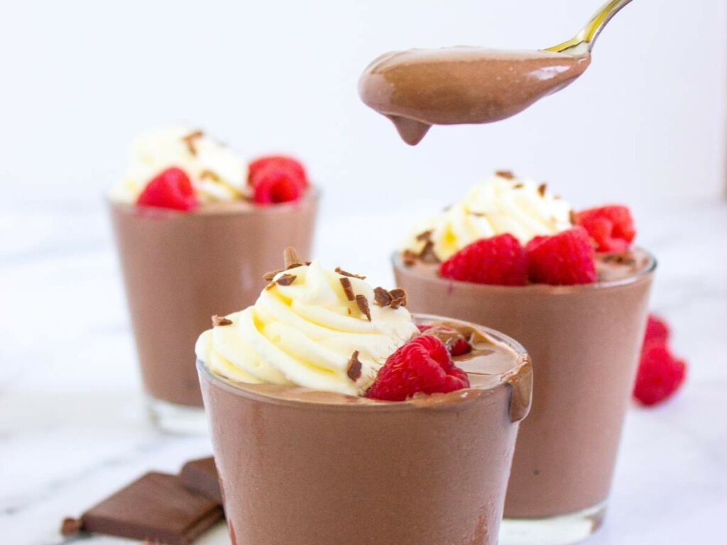Cottage cheese pudding topped with whipped cream, chocolate shavings, and raspberries.