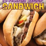 Three Italian beef sandwiches with shredded beef, melted cheese, and peppers on hoagie rolls, displayed on a wooden tray.
