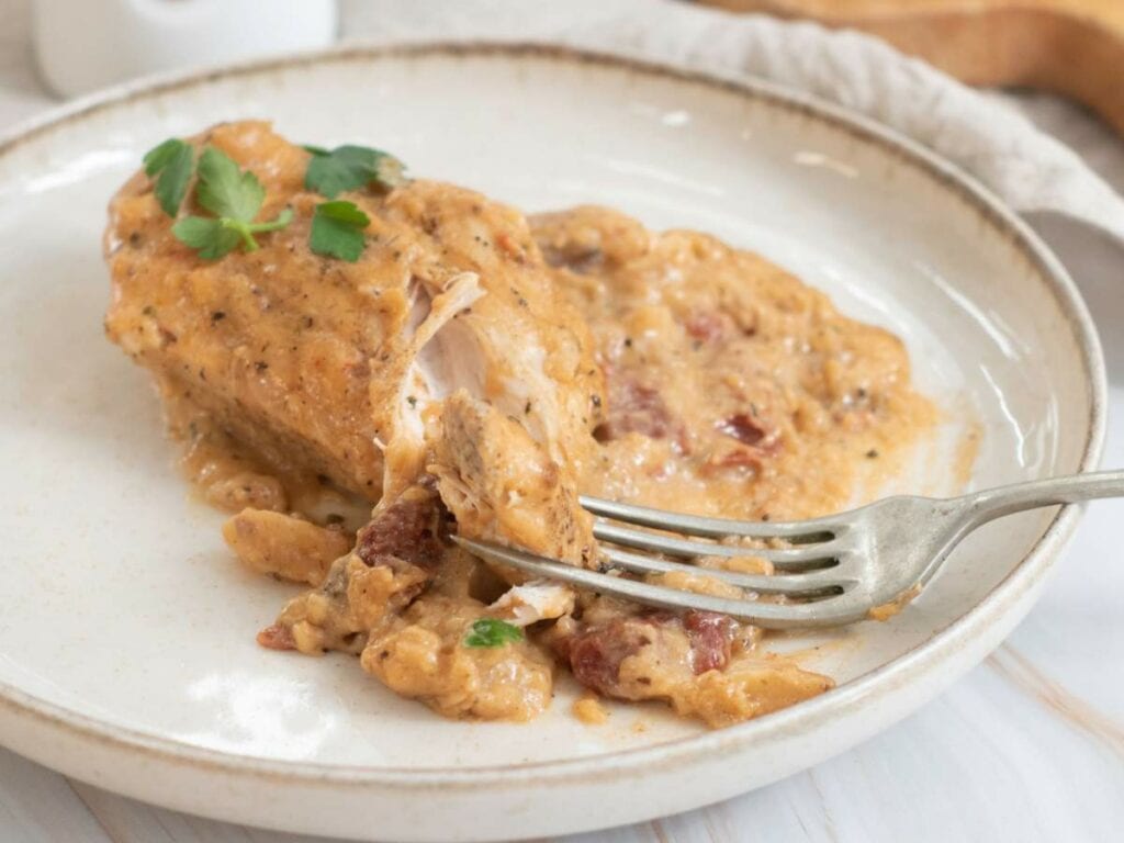 A plate with a piece of marry me chicken skillet, garnished with herbs.