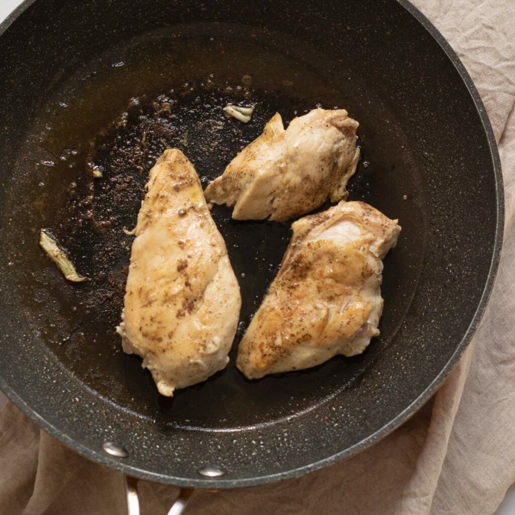 Three cooked chicken breasts seasoned with spices.