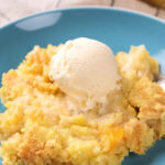 A serving of peach cobbler topped with a scoop of vanilla ice cream on a blue plate.