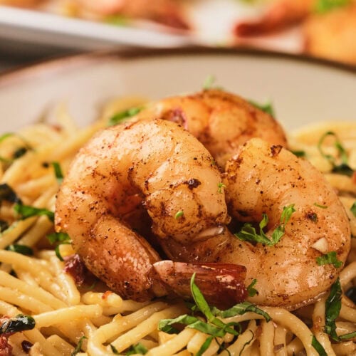 A savory dish of seasoned shrimp served over creamy pasta garnished with herbs.