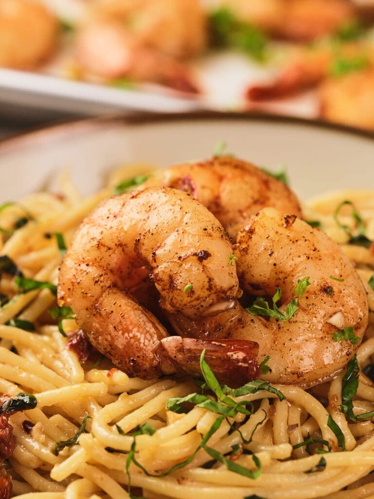A savory dish of seasoned shrimp served over creamy pasta garnished with herbs.