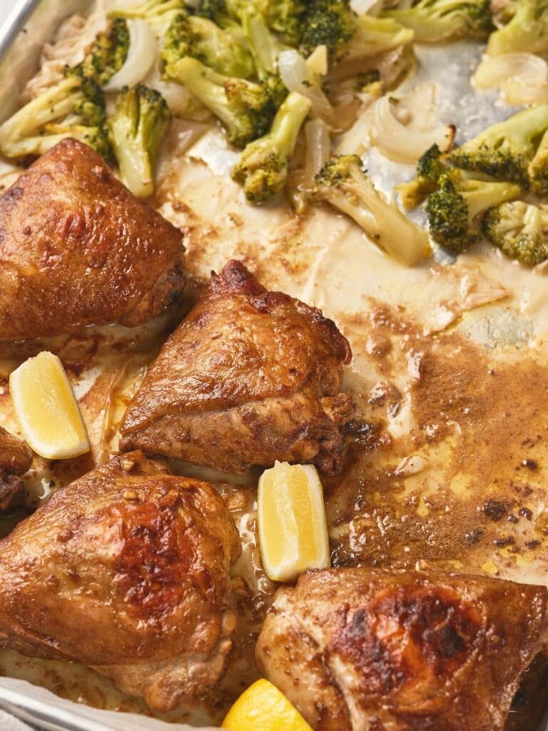 One pan chicken thighs with lemon wedges and roasted broccoli.