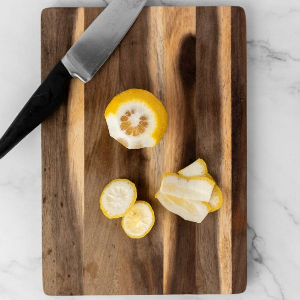 A partially peeled lemon, lemon slices, and peel.